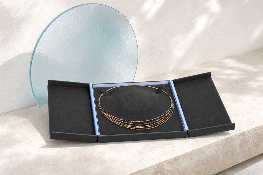 Längliche Collierbox mit beidseitig aufklappenden Seitenteilen, innen mit Collier auf schwarzer Einlage