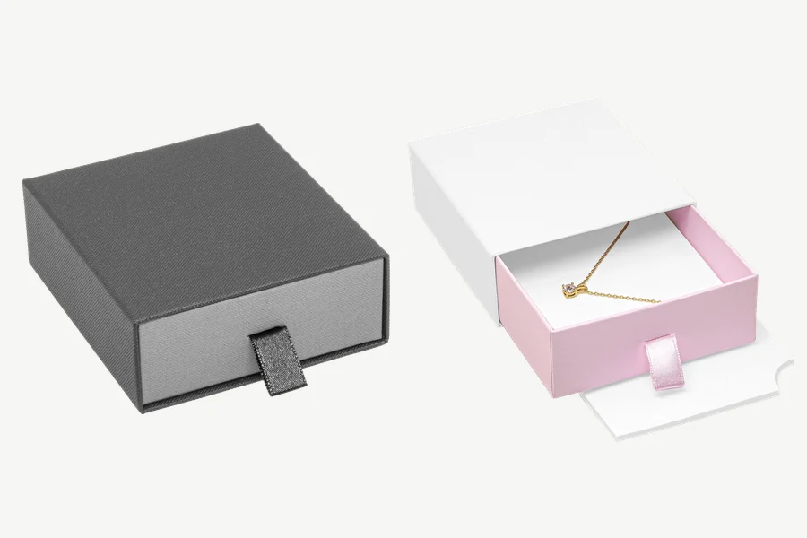 Schiebeschachtel 95 × 85 × 32 mm, links in Dunkelgrau/Hellgrau geschlossen, rechts in Weiß/Rosa mit herausgezogener Lade und Kettenanhänger